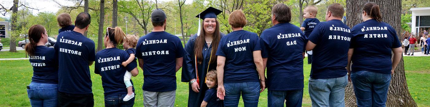 A recent graduate named Rachel poses with family, all of whom are wearing t-shirts with her name on them.