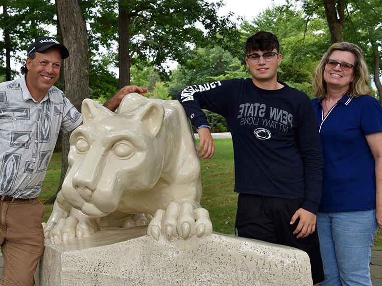 A first-year student poses with his parents in front of the Lion Shrine